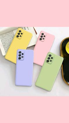 four cell phones sitting next to each other on top of a white table with pink and green cases