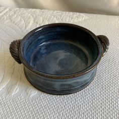 a blue bowl sitting on top of a white cloth covered tablecloth with a knoted edge