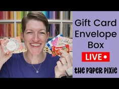 a woman is holding up some cards in front of her face and the words give card envelope box