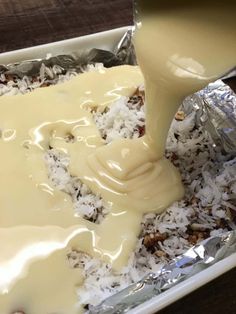 someone pouring milk into a pan filled with rice and other food items on top of aluminum foil