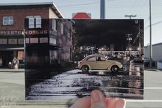 a person holding up a photograph of a car in the rain