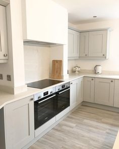 an empty kitchen with white cabinets and wood flooring on the counter top, is pictured in this image