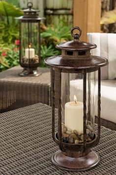 a lit candle sitting on top of a table next to some chairs and tables outside