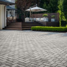 a brick driveway with steps leading up to the house and an umbrella in the middle