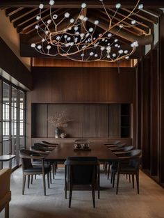 an elegant dining room with wood paneling and lights hanging from the ceiling, along with black leather chairs