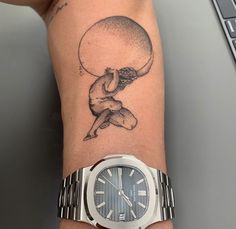 a woman with a tattoo on her arm is holding onto a wrist watch that has a drawing of a man sitting on top of it