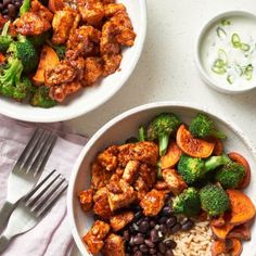 two bowls filled with rice, beans and broccoli on top of a table