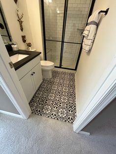 a bathroom with black and white tile flooring next to a walk in shower stall