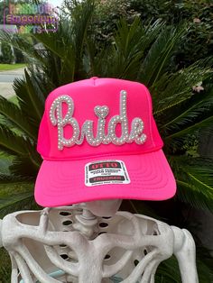 Make a sparkling statement at your bachelorette party or wedding events with this eye-catching rhinestone "Bride" trucker hat! Features: - Classic trucker hat style with mesh back for breathability - Foam front panel with pearl Bride patch secured on front - Adjustable snapback for a perfect fit - Color: Neon Pink front panel with neon pink mesh back -other colors available upon request Perfect for: - Bachelorette parties - Bridal showers - Wedding day getting-ready photos - Honeymoon travel Celebrate your journey from Miss to Mrs in style! This hat is a fun and fashionable way to let everyone know you're the bride-to-be. It's also a great photo prop for those candid bachelorette party shots or casual honeymoon selfies. Care Instructions: Hand wash only. Do not machine wash or dry. Avoid s Honeymoon Selfies, Bachelorette Party Shots, Party Shots, Miss To Mrs, Pearl Bride, Bridal Accessory, From Miss To Mrs, Richmond Hill, Hat Style