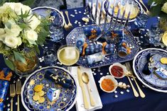 a table set with blue and white plates, silverware and flowers