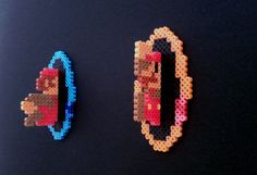 two pieces of bead art on a black surface, one with a red car and the other with a blue car