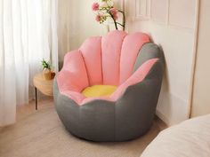 a pink and grey bean bag chair in a bedroom with flowers on the wall behind it