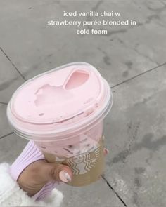 a person holding up a pink starbucks cup