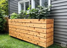 a large wooden planter sitting on top of a grass covered yard next to a house