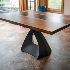 a wooden table sitting on top of a tile floor next to a potted plant