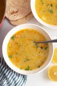 two white bowls filled with soup next to sliced lemons and tortilla chips