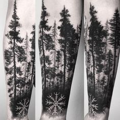 some trees and snowflakes in the woods on this man's leg tattoo