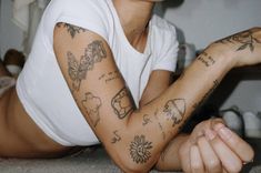 a woman with many tattoos on her arm and chest laying on the floor next to a wall