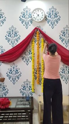 a woman standing in front of a wall with red and yellow garlands on it