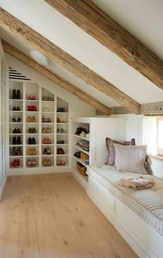 an attic bedroom with white walls and wooden flooring, built in shelving units filled with shoes