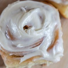 two glazed donuts sitting on top of a wooden cutting board