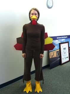 a woman wearing yellow rubber boots standing in front of a wall with a chicken on it's nose