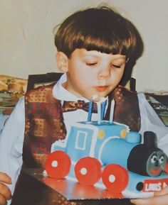 a young boy blowing out the candles on his birthday cake