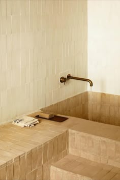 a bath room with a toilet and a wooden bench next to a tiled wall in the corner