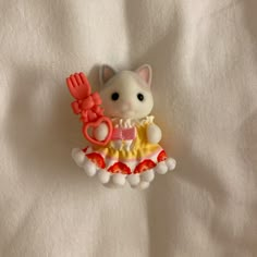 a small white cat with a red bow on it's head sitting next to a toy scissors