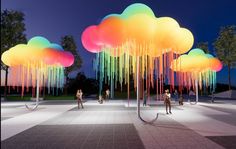 several people are standing in the middle of an open area with multiple colored clouds hanging from them