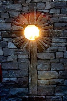 a stone wall with a light shining in it's center and a cross on the side