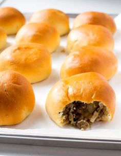 several rolls with meat in them sitting on a baking sheet