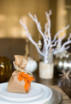 a table with plates, napkins and vases on top of it in brown paper bags