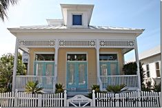 a small white house with a blue front door and two porches on the second floor