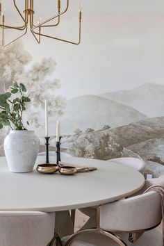 a dining room table with two chairs and a vase on the table next to it