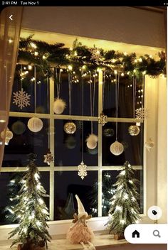 a window decorated for christmas with ornaments and snowflakes hanging from the windowsill