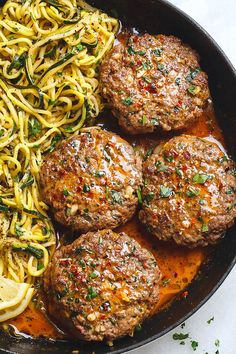 meatballs and pasta in a skillet with lemon wedges on the side, ready to be eaten