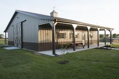 a large metal building sitting on top of a lush green field next to a wooden bench