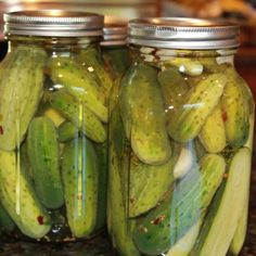 two jars filled with pickles sitting on top of a counter