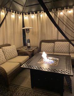 a living room with couches and a fire pit in the middle, surrounded by curtains