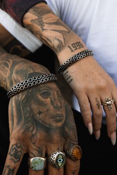 tattooed hands with rings and bracelets on them