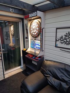 a room with a couch, arcade machine and clock on the wall next to it