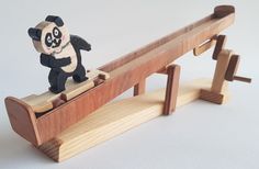 a toy panda bear sitting on top of a wooden bench