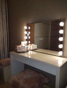 a vanity with lights on it and a stool in front of the mirror that is lit up