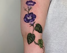 a purple flower with green leaves on the arm