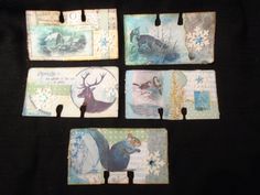 four tags with animals and snowflakes are on a black tablecloth covered surface