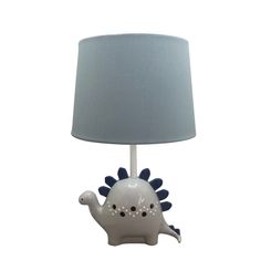 a white lamp with a blue shade on it and a small dinosaur figurine underneath