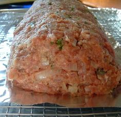 the meatloaf is covered with onions and seasoning sitting on top of foil