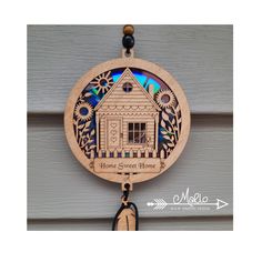 a wooden clock hanging from the side of a door with a house design on it