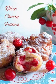 some cherry pastries are on a plate with powdered sugar and fresh cherries